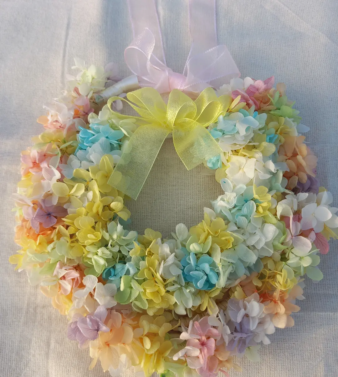 ハワイの伝統文化レイメイキングで編んだウェディング花冠とハワイアンリース。祈りと癒しと光を宿すオリジナルハンドメイド作品。虹が子を包むようなイメージで撮影。